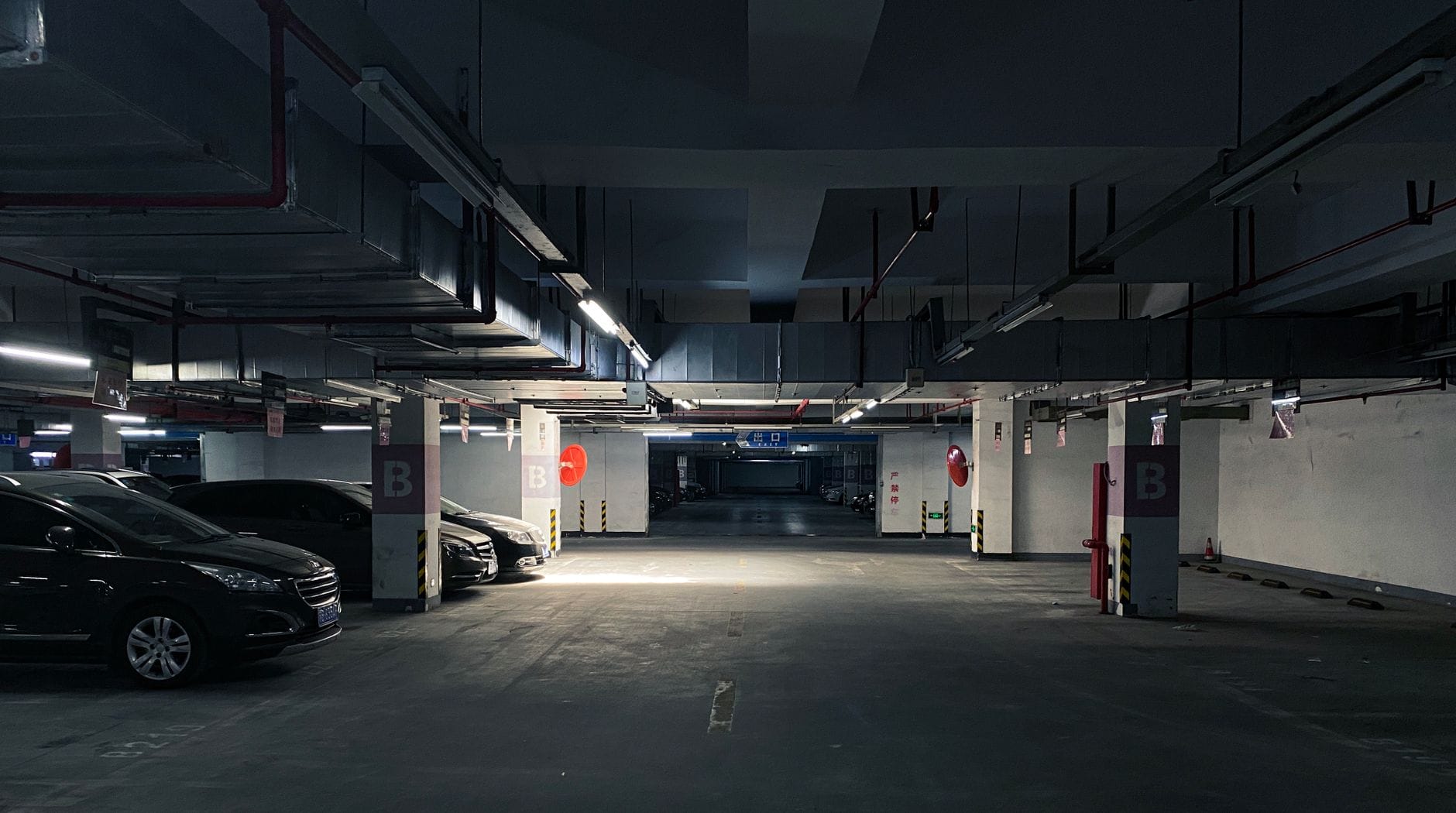 Ciemny parking podziemny z zaparkowanymi samochodami i słabym oświetleniem