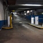 Wjazd do podziemnego parkingu z barierkami i słabym oświetleniem