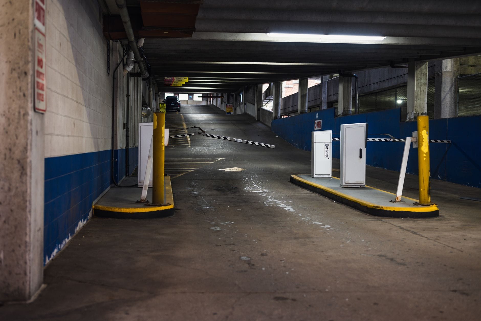 Wjazd do podziemnego parkingu z barierkami i słabym oświetleniem