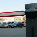 Zbliżenie na automatyczny szlaban parkingowy i auta w tle