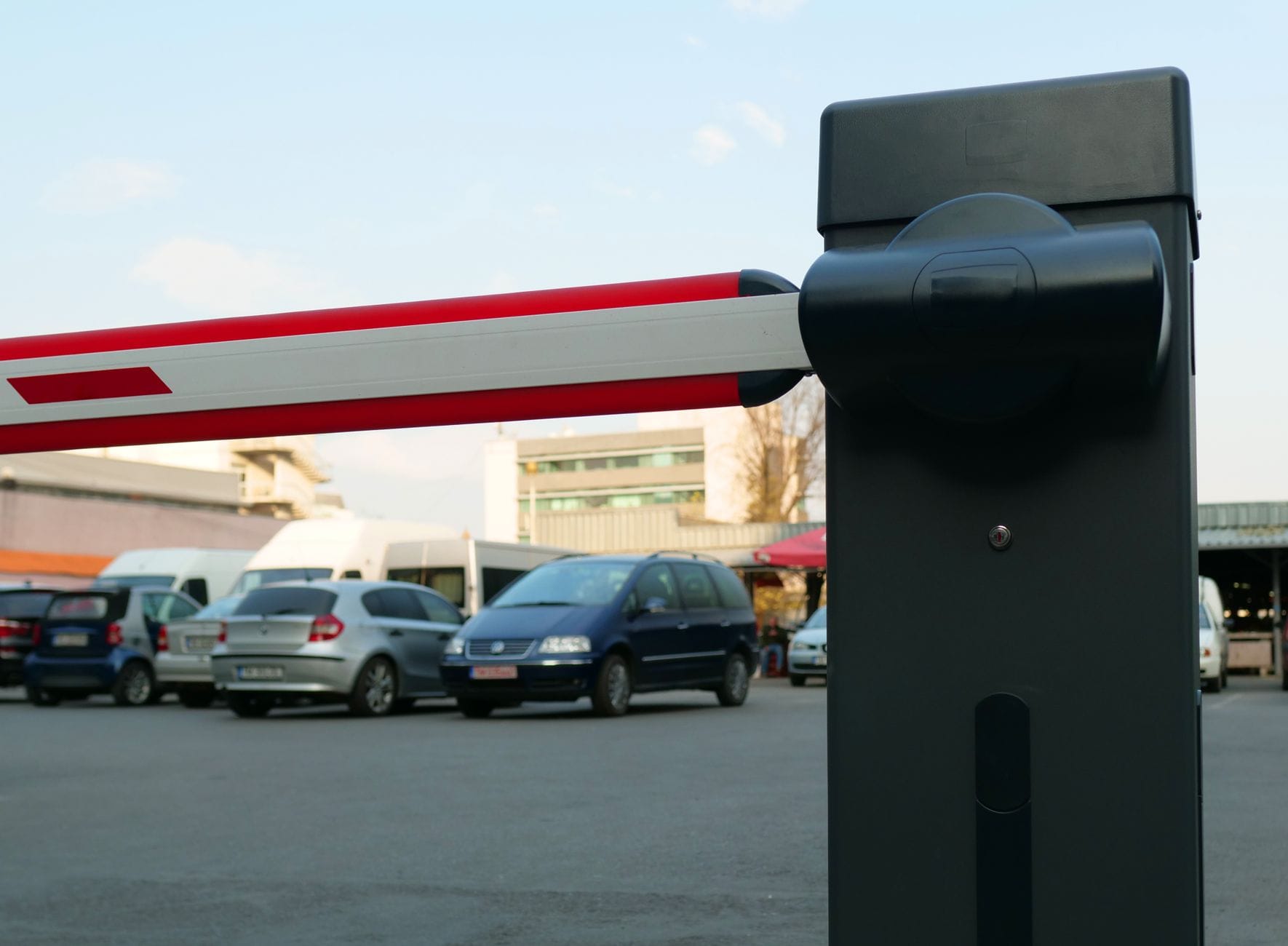 Zbliżenie na automatyczny szlaban parkingowy i auta w tle